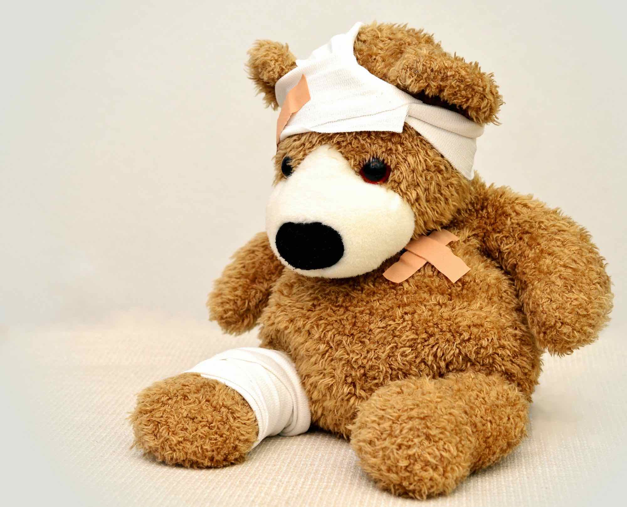 Photo of a teddy bear looking sad covered in bandages and plasters